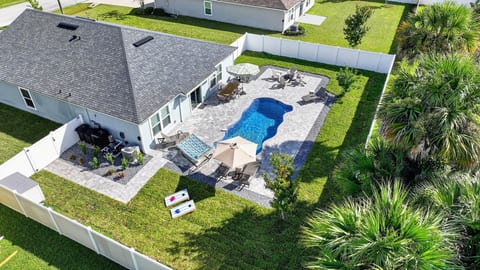 Private fenced backyard with pool, patio seating, and tropical ambiance