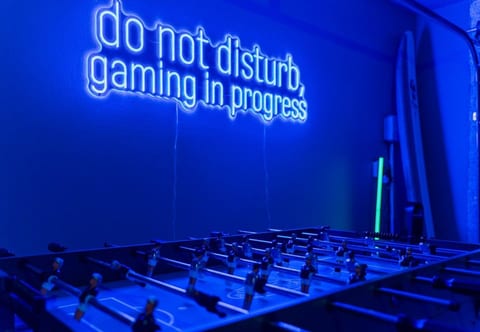 Neon-lit game room with foosball—perfect for late-night fun.