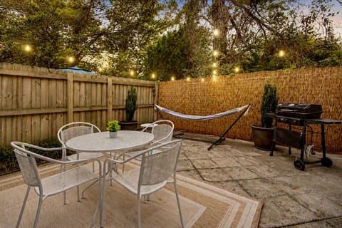 Cozy private patio with hammock, grill, and string-lit outdoor dining