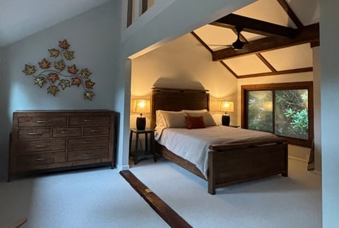 Cozy loft bedroom with vaulted beams and serene forest views