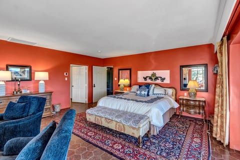 Spacious king bedroom with warm decor, cozy seating, and timeless style