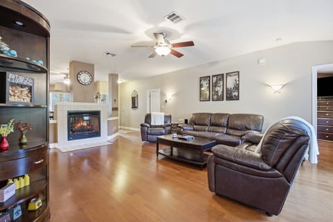 Spacious living room with fireplace, leather seating, and warm wood floors