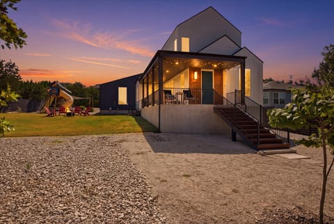 Modern home with glowing porch, big yard, and family-friendly outdoor space