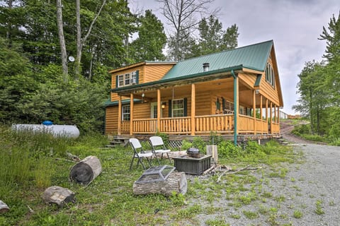 Rustic woodland cabin with wraparound porch and outdoor fire pit
