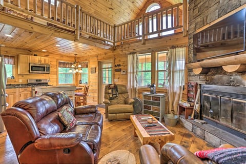 Cozy log cabin great room with stone fireplace, loft, and open kitchen