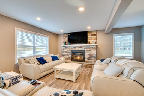 Cozy living room with stone fireplace, big TV, and bright comfy seating