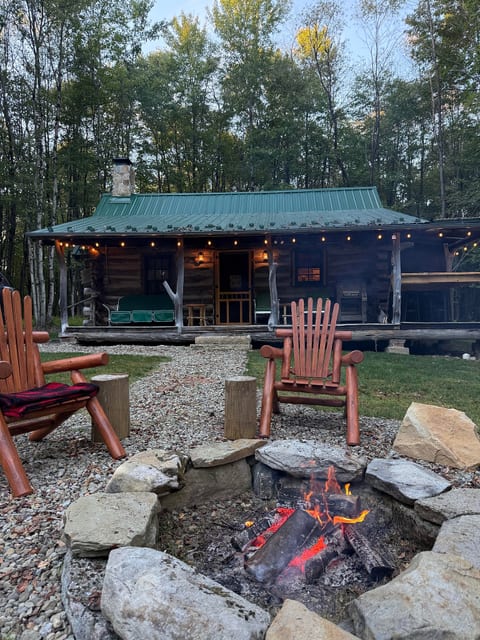 Cozy woodland cabin with string-lit porch and inviting fire pit seating