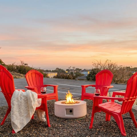 Patio Retreat: Gather around the fire pit with ocean views and vibrant red chairs!