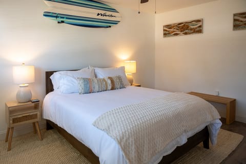 Coral House 2BR – Bedroom 2: queen bed under the surfboard – boho coastal all the way