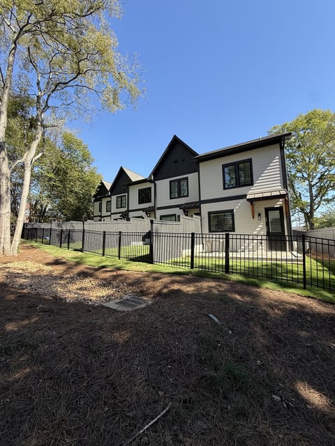 Modern home exterior with fenced yard and peaceful tree-lined setting