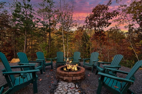 Gather around the stone firepit under the trees — Adirondack seating for the whole group as the sky turns pink.