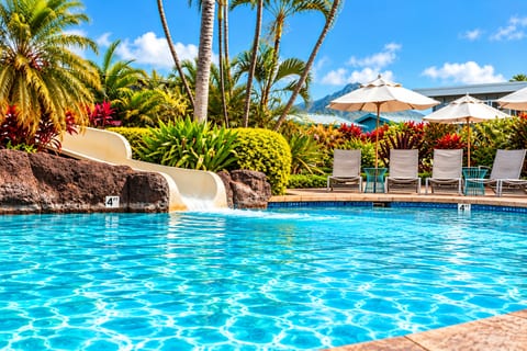 Resort-style pool with waterslide, tropical landscaping & Kauai mountain views at the Poipu Beach Club.