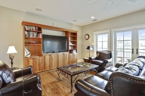 Great game room with large 65 inch curved 4k smart TV, shuffleboard, board games, and balcony overlooking golf course.