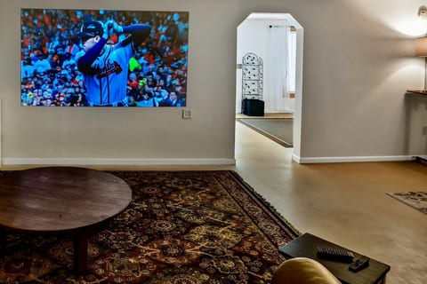 Game day, larger than life: the projector throws a big-screen picture across the lounge wall, above a richly patterned rug and round coffee table. Owl's Rest, Ellijay, GA.