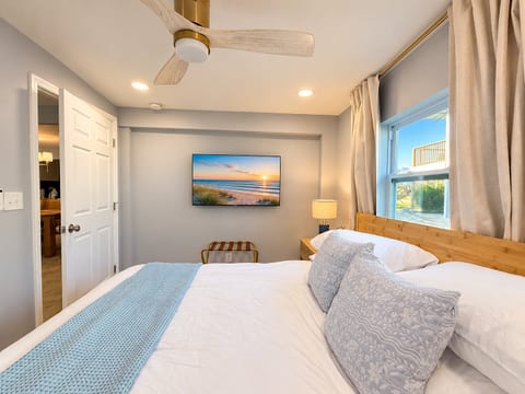 Bright coastal-style bedroom with plush king bed and natural light