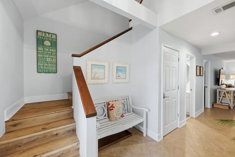Bright coastal entryway with warm wood stairs and charming beach decor