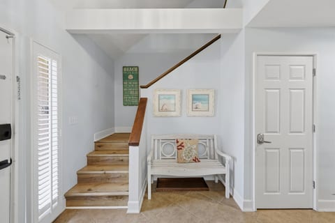 Bright coastal entryway with natural light, wood stairs, and charming decor