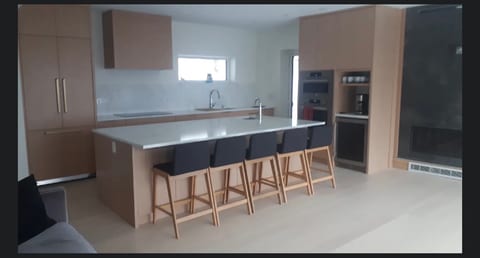 Sleek kitchen with inviting island seating. Large meal prep area with modern appliances and beverage fridge.