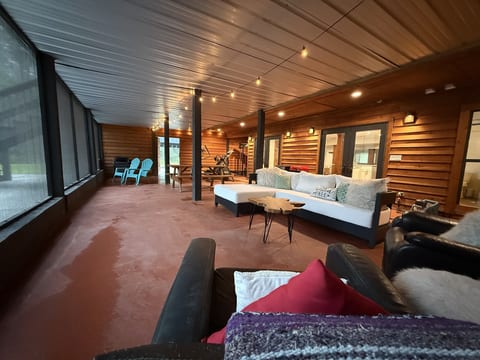 Spacious screened porch with cozy seating, string lights, and room to gather