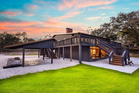 Two complete residences in one modern barndominium-style home. Downstairs lit at dusk. Four bedrooms, five bathrooms, two full kitchens. Canal-front on Weeks Bay.