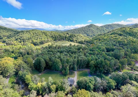 An aerial look at Robbin’s Nest on Snowbird Creek and its creekside setting, surrounded by wooded hills and the mountains of Western North Carolina.