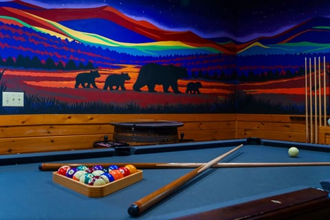 Cozy game room with pool table and stunning mountain bear mural