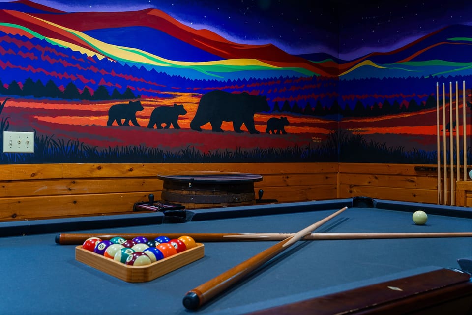 Cozy game room with pool table and stunning mountain bear mural