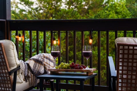 Cozy private balcony with wine, string lights, and serene forest views