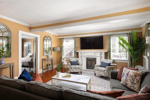 Elegant first floor living room featuring comfortable seating, a fireplace, large windows, and classic Key West architectural details.