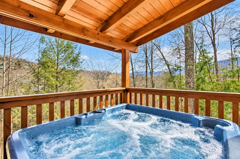 Private hot tub on a covered deck with peaceful wooded mountain views
