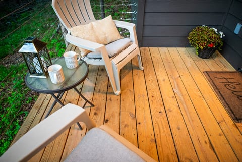 Cozy private deck with seating, coffee setup, and peaceful wooded views