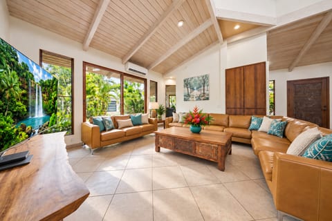 Gather together in Hemolele’s spacious living room with soaring vaulted ceilings and tropical views.