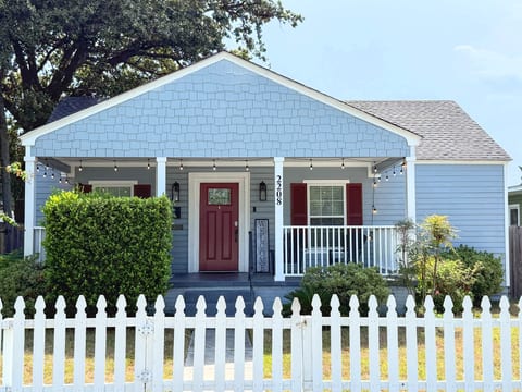 Charming cottage with a front porch, string lights, and white picket fence