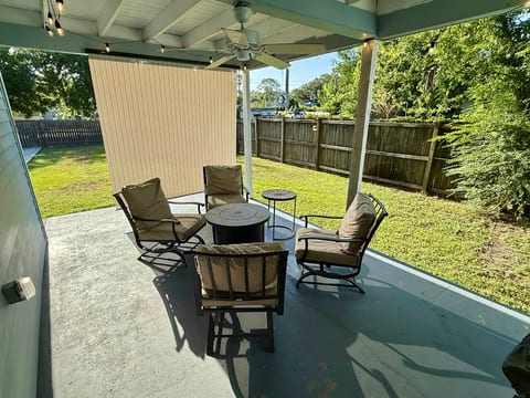 Covered patio with fire pit seating and a private fenced yard