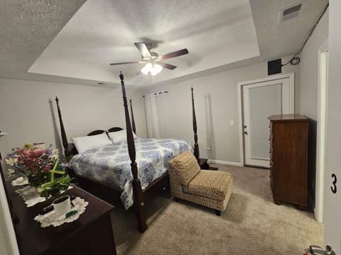 Spacious and comfortable bedroom featuring a king-size bed, cozy carpeting, and ceiling fan. Thoughtfully arranged to provide a relaxing and restful space during your stay.