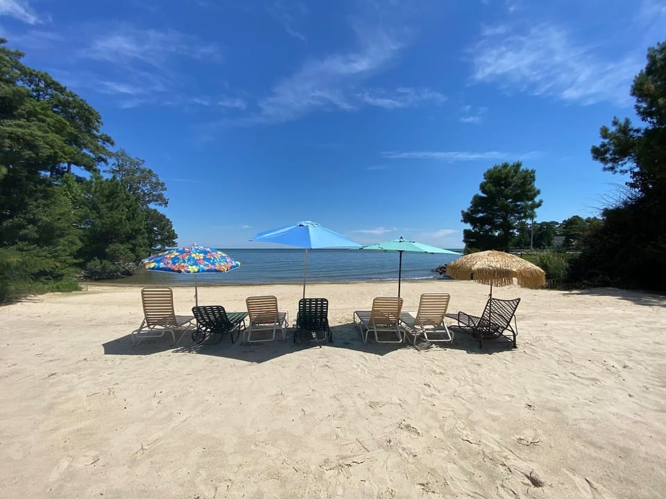 Exclusive beachfront with direct Chesapeake Bay access, featuring outdoor seating and umbrellasâperfect for relaxing, enjoying ocean breezes, and watching stunning sunsets right from the sand.