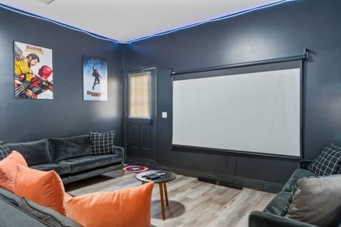 Cozy home theater room featuring a large projector screen, comfy seating, and Marvel-themed decor—perfect for movie nights!