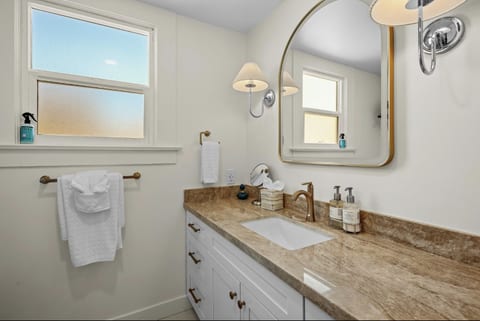 A spacious vanity with stone countertop, arched mirror, and plenty of storage.