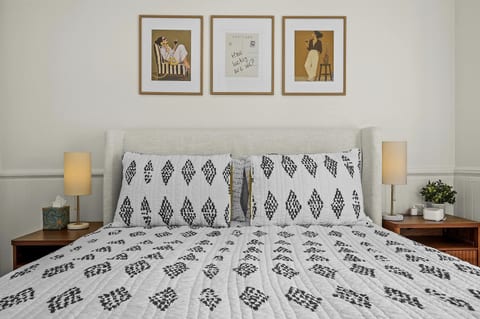 The second bedroom features a queen bed with an upholstered headboard, matching nightstands with lamps, and curated artwork.