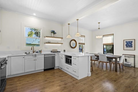An open and airy kitchen and dining area with white cabinetry, stainless steel appliances, and plenty of natural light.
