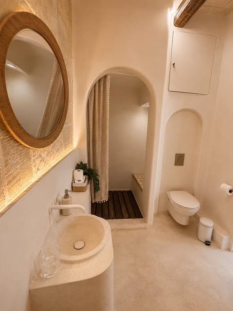 Spa-like bathroom with stone sink, warm lighting, and arched shower entry