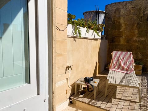 Sunny private patio with lounger, warm stone walls, and charming details
