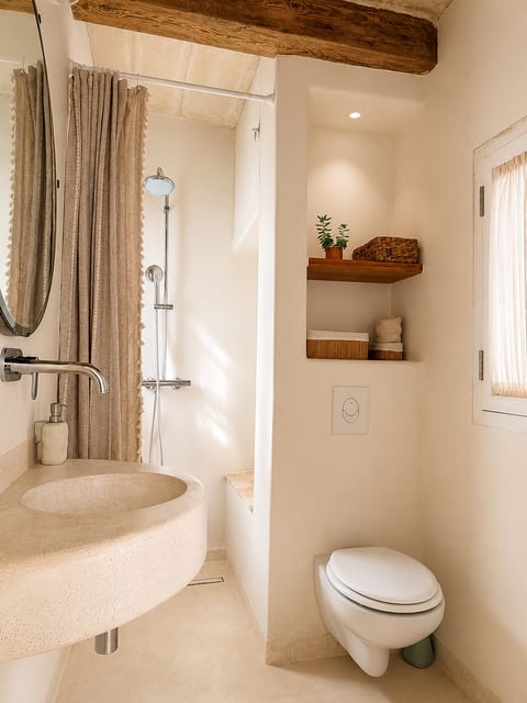 Bright spa-style bathroom with rustic beams and elegant stone sink