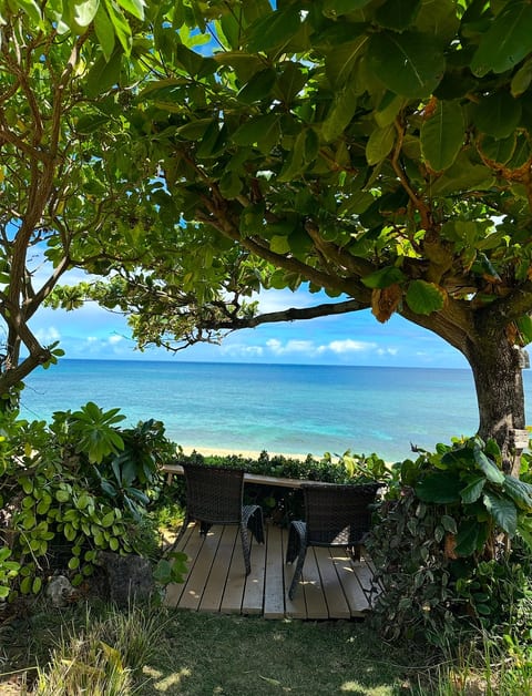 Shaded oceanfront yard with a small deck and seating.