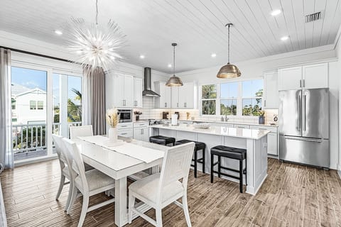 Bright, open kitchen and dining area with a large island, stainless steel appliances, plenty of seating, and direct access to the covered porch.