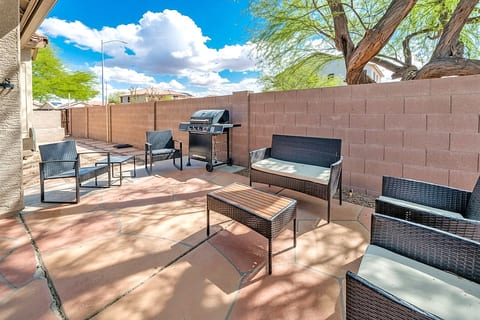 Sunny patio with grill, wicker seating, and private walled yard