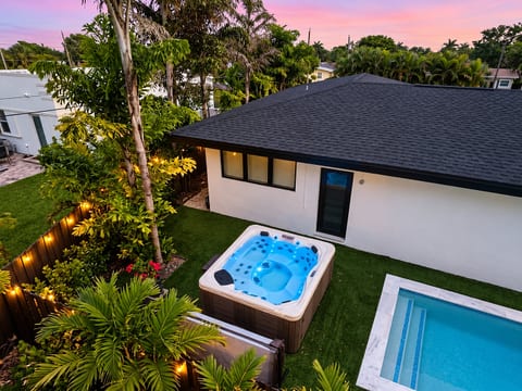 Private tropical backyard with Unwind in the private hot tub surrounded by tropical greenery and warm evening lights.pool, hot tub, and glowing evening ambiance