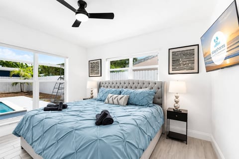 Bright king bedroom with pool views, TV, and serene coastal style