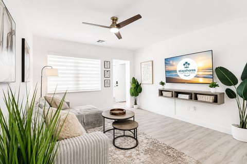 Bright modern living room with large TV, cozy seating, and airy natural style