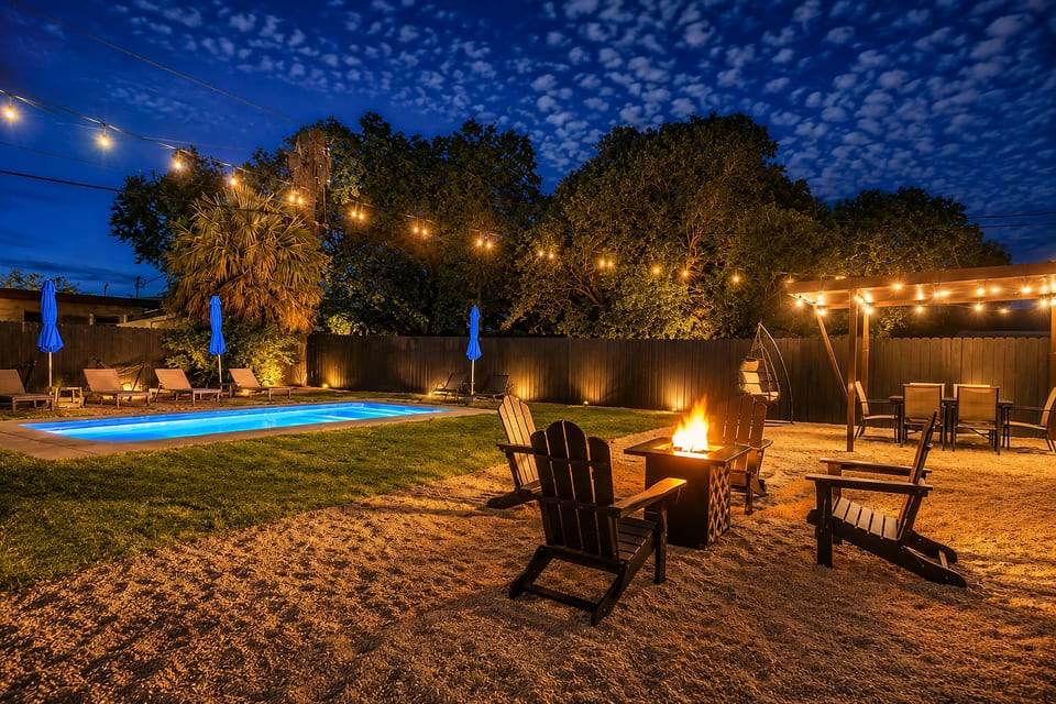 Resort-style backyard with pool, fire pit, and twinkling evening lights
